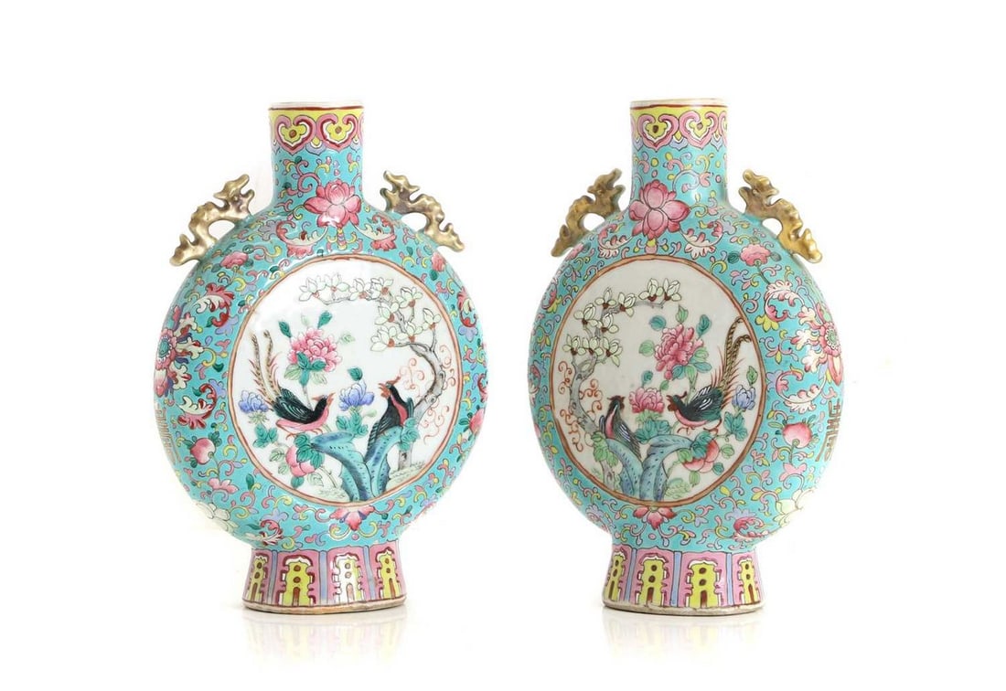 A pair of Chinese famille rose moon flasks,: A pair of Chinese famille rose moon flasks, 20th century, the compressed circular body decorated with pheasants among blossoming flowers or figures, flanked by dragon handles to the shoulder, 25cm hig