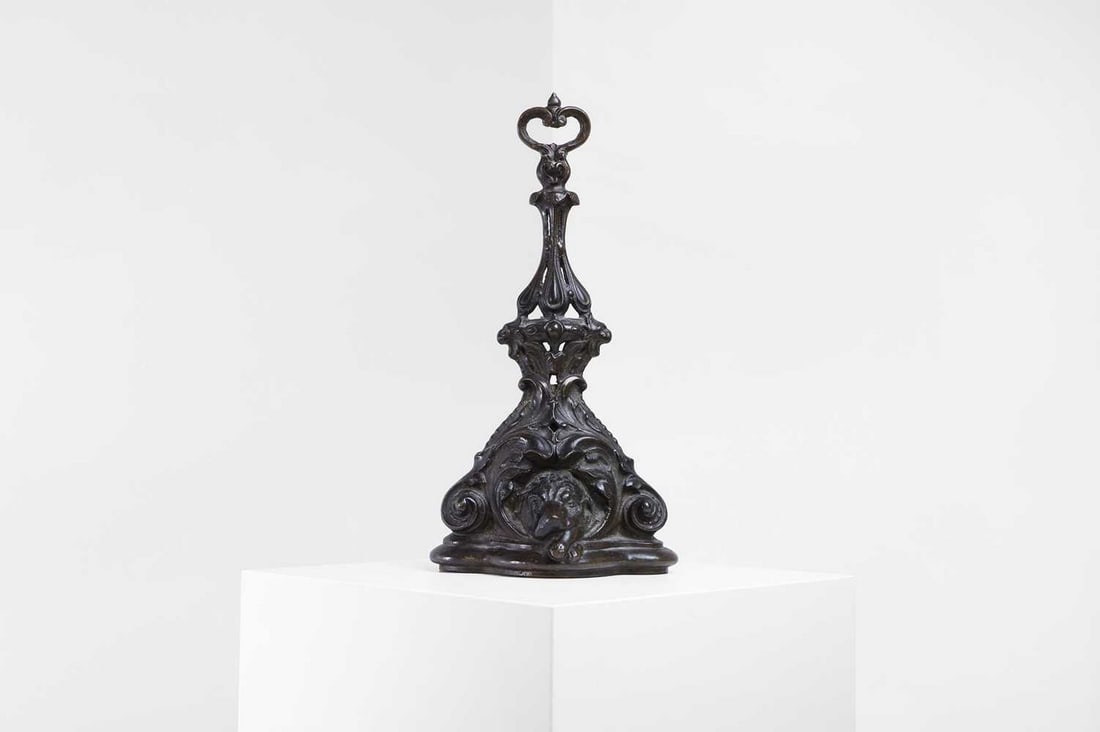 A late Victorian cast iron doorstop,: A late Victorian cast iron doorstop, late 19th/early 20th century, cast with scrolling foliage on a tripartite base centred with a dog's mask, 19cm wide 10cm deep 40cm high Condition Report: Light wea