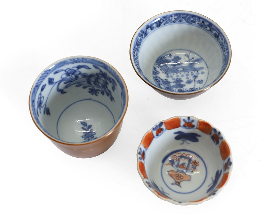 Two Chinese blue and white tea cups,: Two Chinese blue and white tea cups, Kangxi (1662-1722), the interior painted with precious objects or a landscape, the exterior in cafe-au-lait, 4.5 and 6.5cm high and a Chinese Imari cup, Kangxi, of