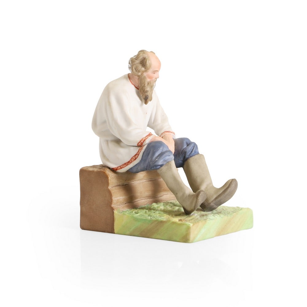 A Gardner bisque porcelain figure,: A Gardner bisque porcelain figure, late 19th century, of an old Jewish man seated on a bench, red printed marks and impressed '21', 9cm wide 12cm deep 15cm high Condition Report: Right leg reset, flak