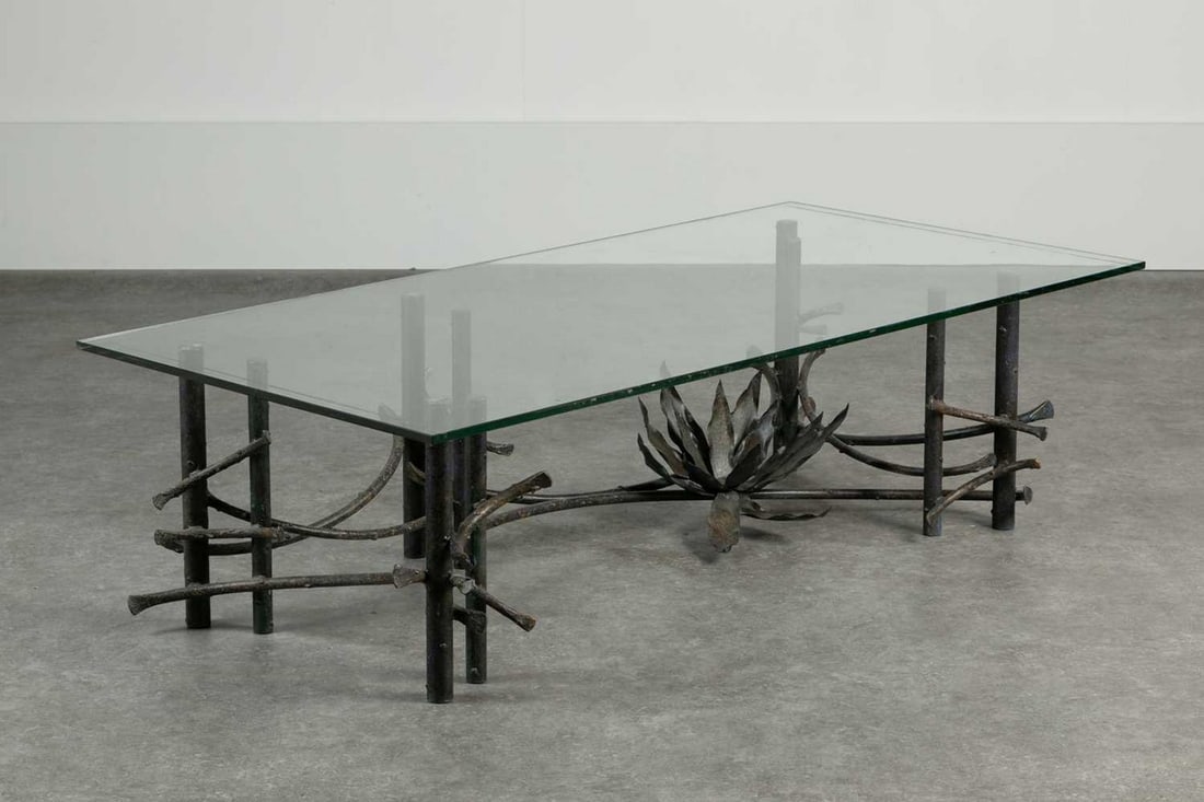 A patinated wrought-iron and glass coﬀee table,: A patinated wrought-iron and glass coﬀee table, 1970s, in the manner of Silas Seandel, naturalistically modelled with columns, scrolls and centred with a flower, 143cm wide 70.5cm deep 39.5cm h