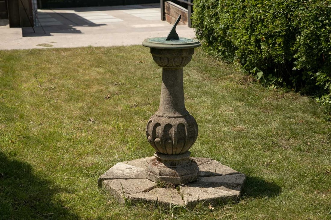 A Cotswold stone sundial,: A Cotswold stone sundial, late 19th century, mounted with a bronze plate and gnomon, inscribed 'Cary's, London', on a slate top, stone column, and raised on a hexagonal sectional stone base, dial 27.5