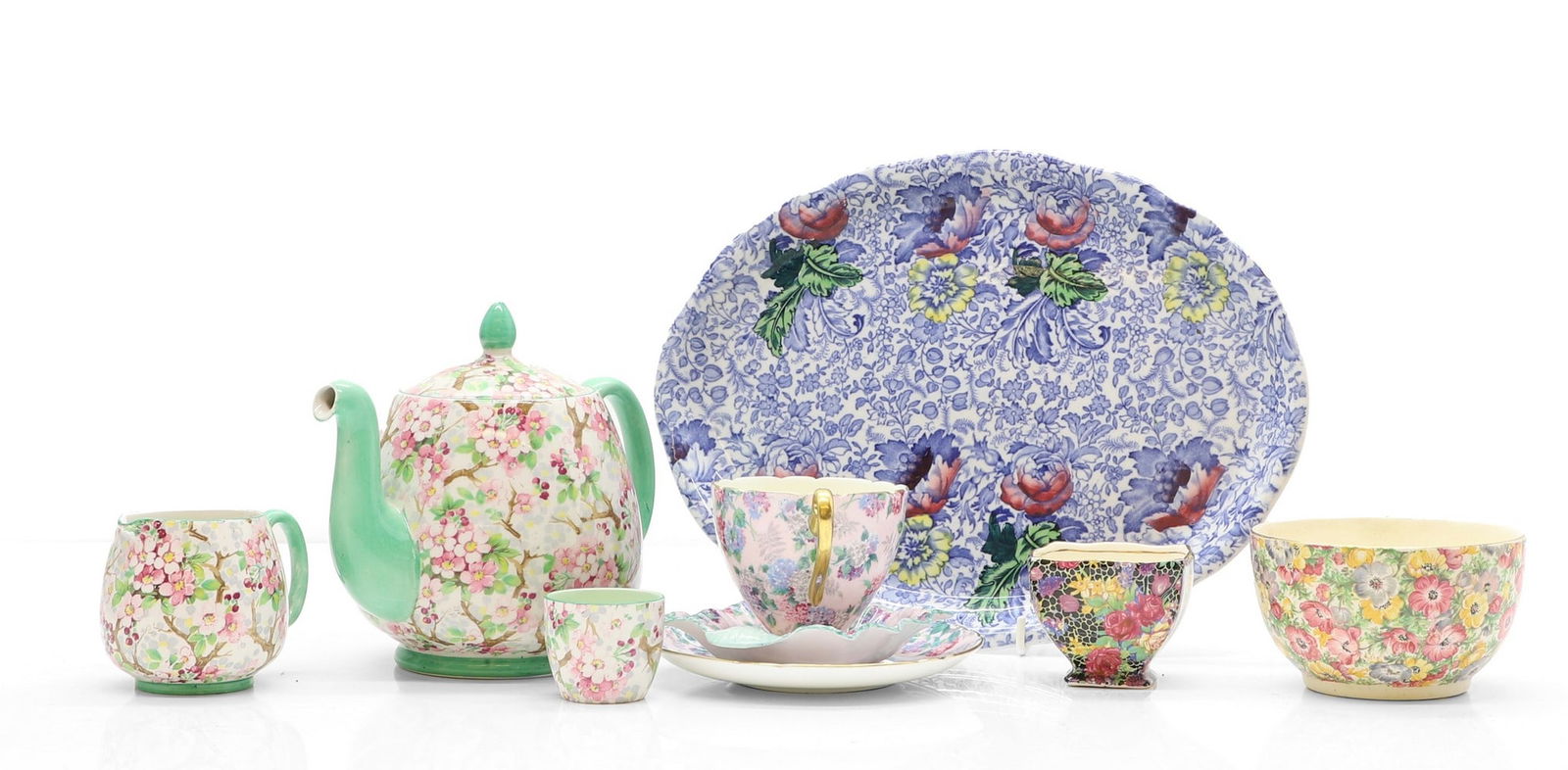 A Shelley 'Maytime' pattern tea pot,: A Shelley 'Maytime' pattern tea pot, 18cm wide, creamer, 7cm high, egg cup 4.2cm high, each with cherry blossom decoration to a cream ground, and green borders, and a Shelley 'Summer Glory' pattern te