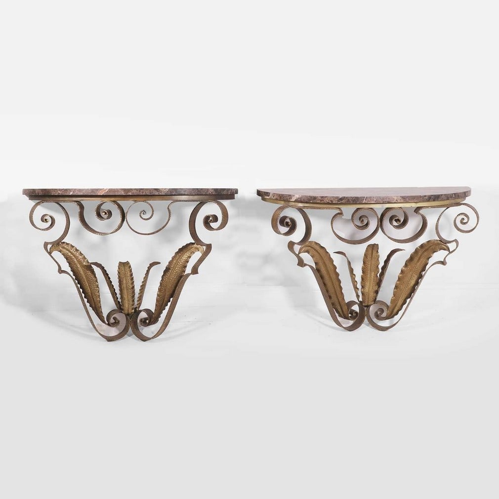 Pier Luigi Colli (Italian, 1895- 1968),: Pier Luigi Colli (Italian, 1895- 1968), a pair of wall-mounted console tables, c.1940s, each demilune marble top over a gilded metal base with scrolled detailing, 105cm wide 39cm deep 70cm high (2)