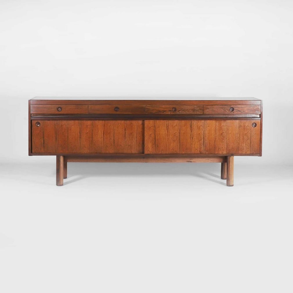 § Robert Heritage (1927-2008) for Archie Shine,: § Robert Heritage (1927-2008) for Archie Shine, a rosewood sideboard, c.1970s, with four drawers above two sliding doors, opening to reveal two cupboards, supported on four cylinder feet, 211cm w