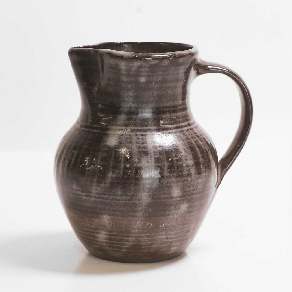 Michael Cardew (1901-1983) for Abuja Pottery,: Michael Cardew (1901-1983) for Abuja Pottery, a glazed stoneware jug, with running iron glaze, 1950-60s, impressed maker's mark and pottery mark, 14cm wide 12cm deep 15.5cm high