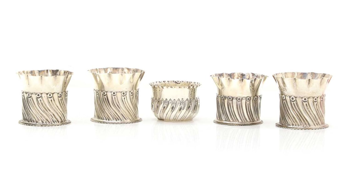 A set of four silver bottle coasters or holders,: A set of four silver bottle coasters or holders, by Goldsmiths & Silversmiths Co (William Gibson & John Lawrence Langman), London 1891-1892, 8cm wide, together with one other similar, by Char