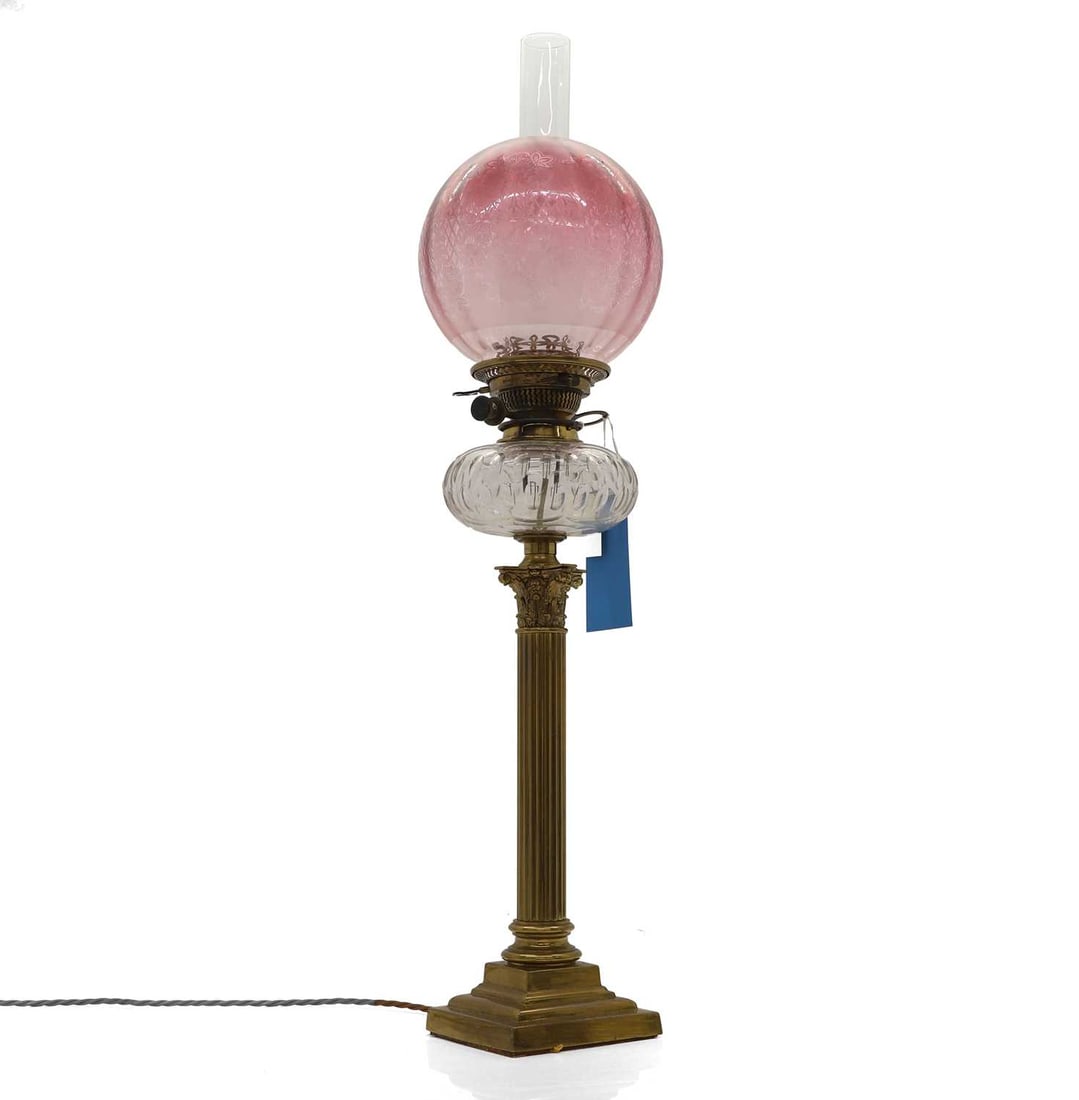 A duplex brass oil lamp,: A duplex brass oil lamp, the etched globular ruby glass shade above clear glass reservoir on brass Corinthian column stand, coverted to electric78cm high Condition Report good overall condition, some