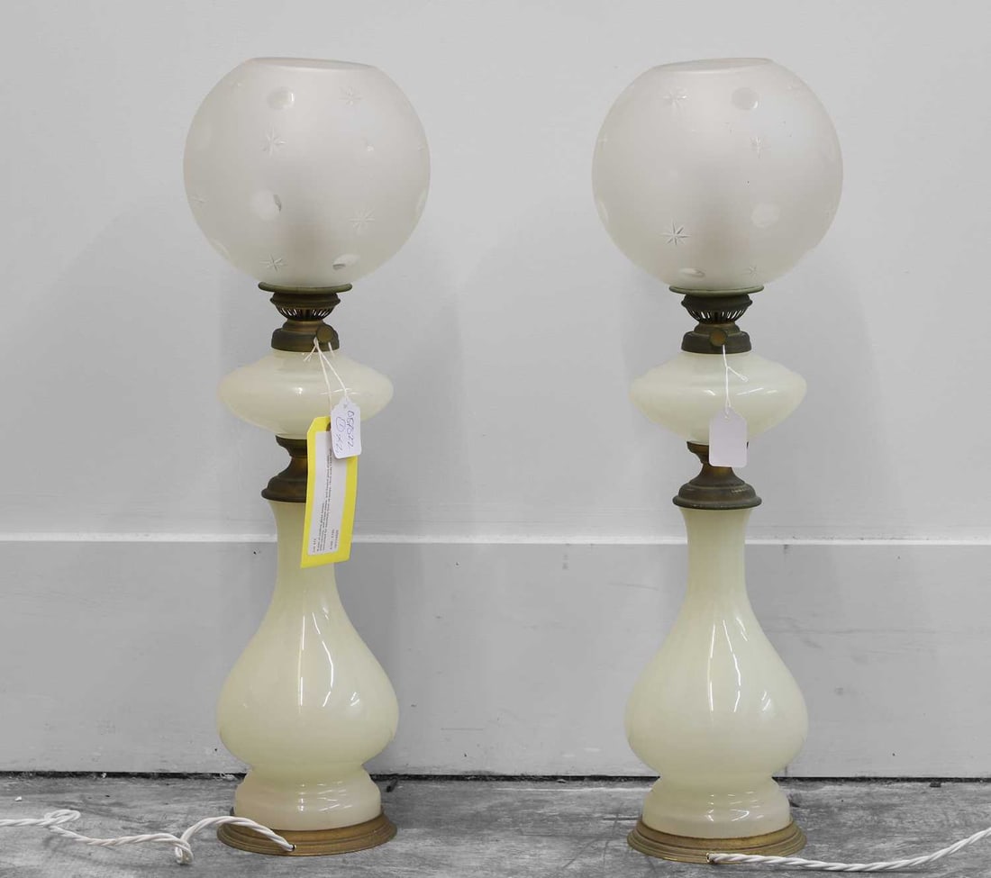 A pair of opaline glass lamps,: A pair of opaline glass lamps, 20th century, with brass bases, and frosted glass shades, converted for electricity from oil lamps,19cm wide 74cm high Condition Report We can