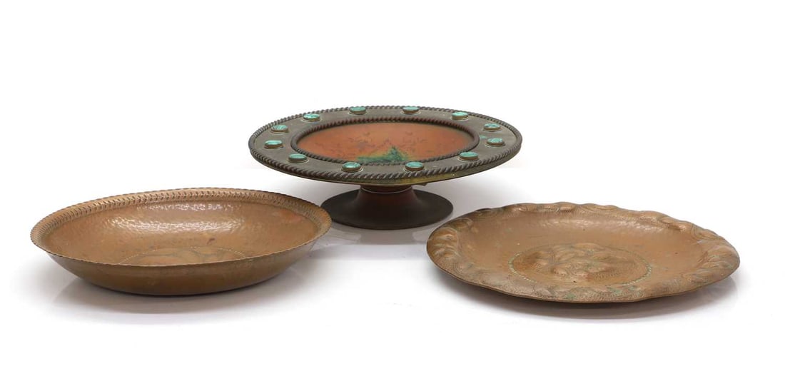 A brass tazza inset with malachite,: A brass tazza inset with malachite, with star design to the centre,32.5cm diameter10cm hightogether with two Arts and Crafts embossed brass dishes,30cm and 32cm diameter (3)Provenance: An