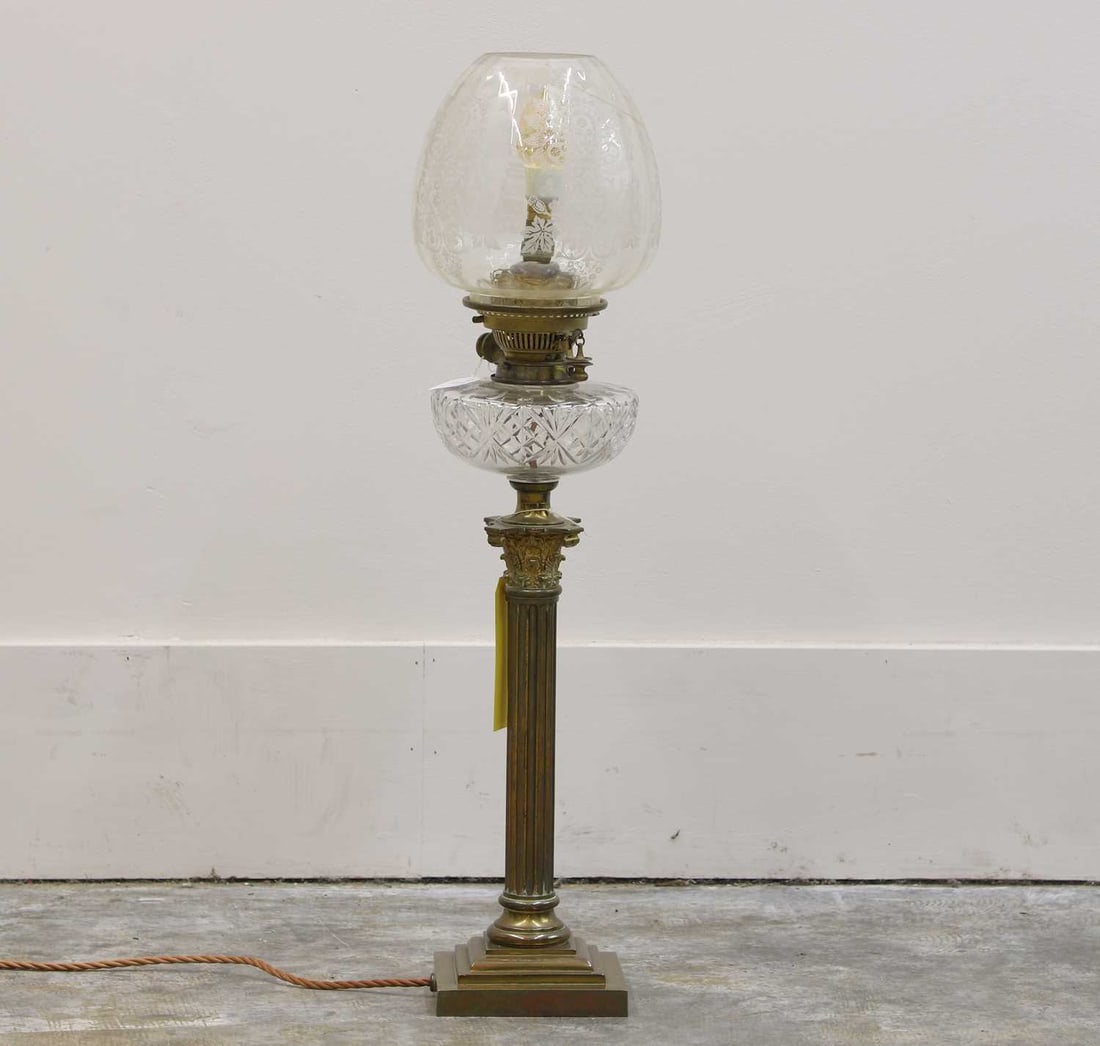 A Victorian oil lamp,: A Victorian oil lamp, raised on a Corinthian column and stepped base, with moulded glass reserve, 19cm wide 74cm high Condition Report converted to electricity – crack to shade