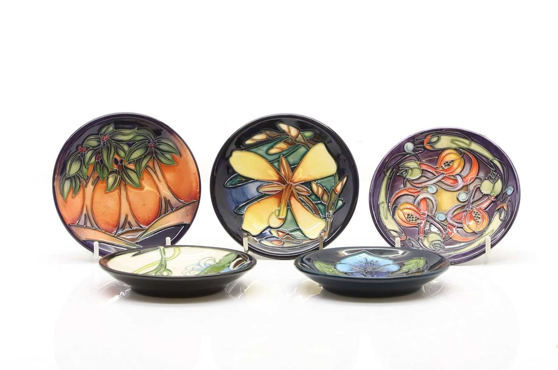 A collection of five Moorcroft coasters,: A collection of five Moorcroft coasters, comprising 'New Forest' pattern, 12cm wide, 'Lily Plume', 12cm wide, 'Triple Choice', 12cm wide, 'Carnival', 12cm wide, and 'Panache', 12cm wide, incised and