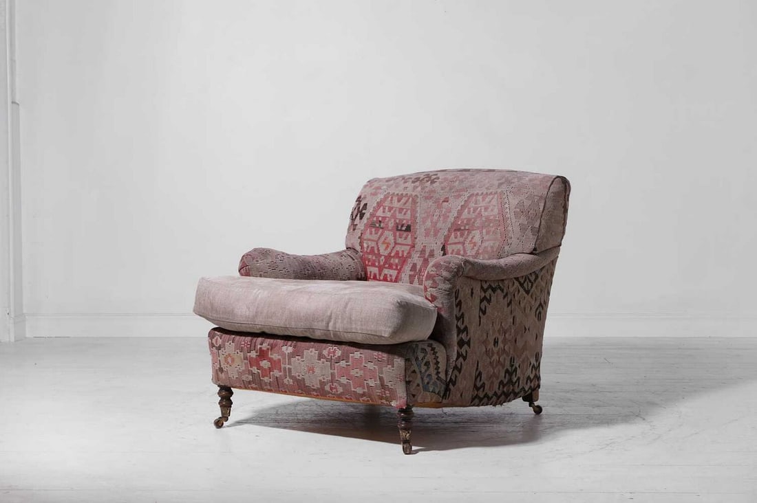 A kilim-upholstered armchair by George Smith,: A kilim-upholstered armchair by George Smith, c.1990, with roll arms and a loose cushion upholstered in herringbone fabric, raised on ring-turned beech supports terminating in brass caps and castors,