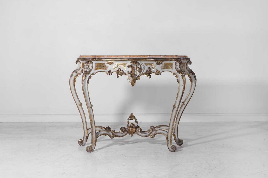 A carved, painted and giltwood console table in the rococo taste,: A carved, painted and giltwood console table in the rococo taste, 19th century, Italian, of serpentine outline with a Siena marble top, above a foliate-carved frieze, and cabriole supports united by s