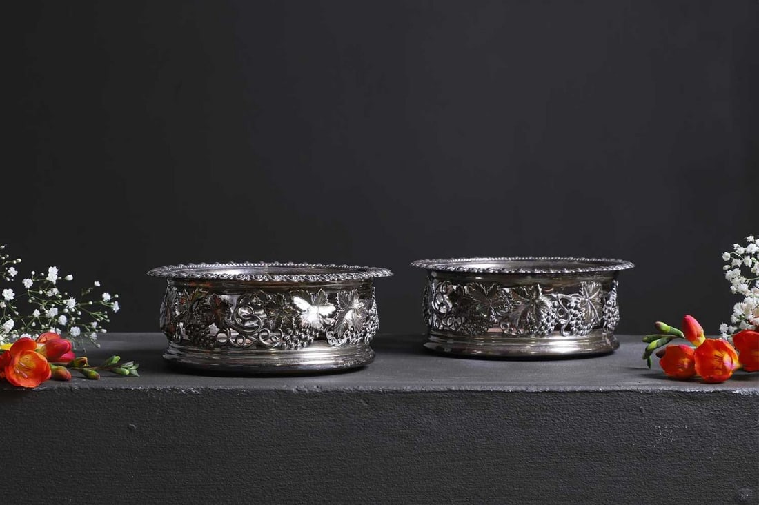 A pair of George IV silver coasters,: A pair of George IV silver coasters, Sheffield 1823, each with an egg-and-dart rim over pierced sides worked with fruiting vines, on a turned wooden base, 15cm diameter 6cm high (2) Provenance: An Eas