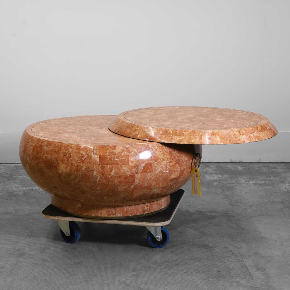 A low tesserae and brass-mounted side table 20th century: A low tesserae and brass-mounted side table 20th century Of drum form with a circular top, pivoted to extend, with a pair of ring handles 854cm diameter, 41cm highCondition Report: Some knocks and ch