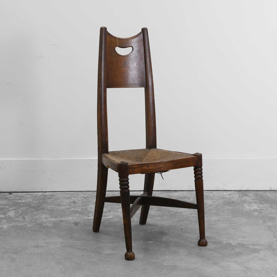 An Arts and Crafts ash side chair Circa 1900: An Arts and Crafts ash side chair Circa 1900 Designed by George Walton for William Birch, with a tapering back, a fret cut splat, a rush seat, over ring turned supports, united with an 'X' stretcher