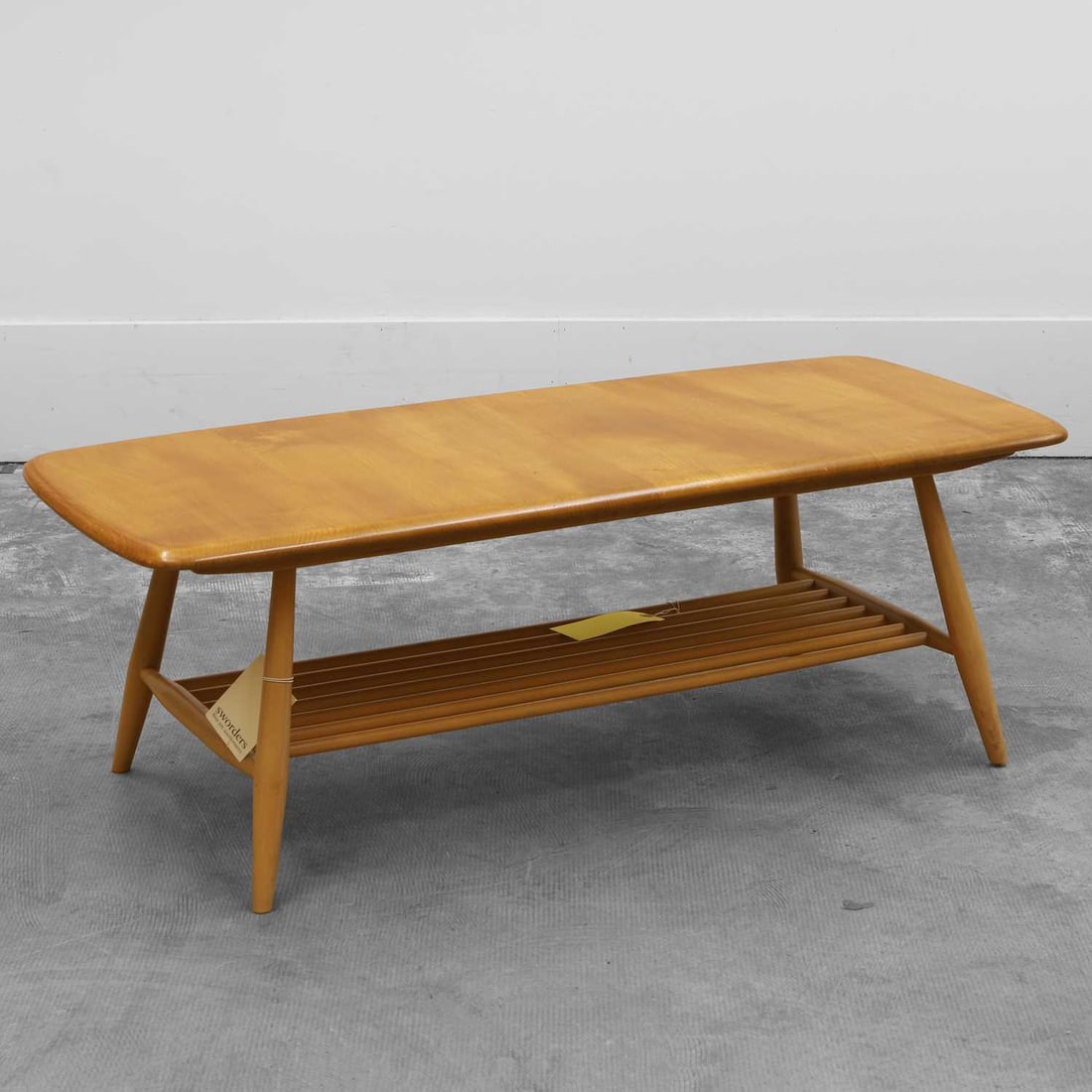 An Ercol 'Windsor' beechwood low table 20th century: An Ercol 'Windsor' beechwood low table 20th century The rounded rectangular top raised on turned supports united by a spindled undertier 104cm wide, 46cm deep, 36cm highCondition Report: A few surfac