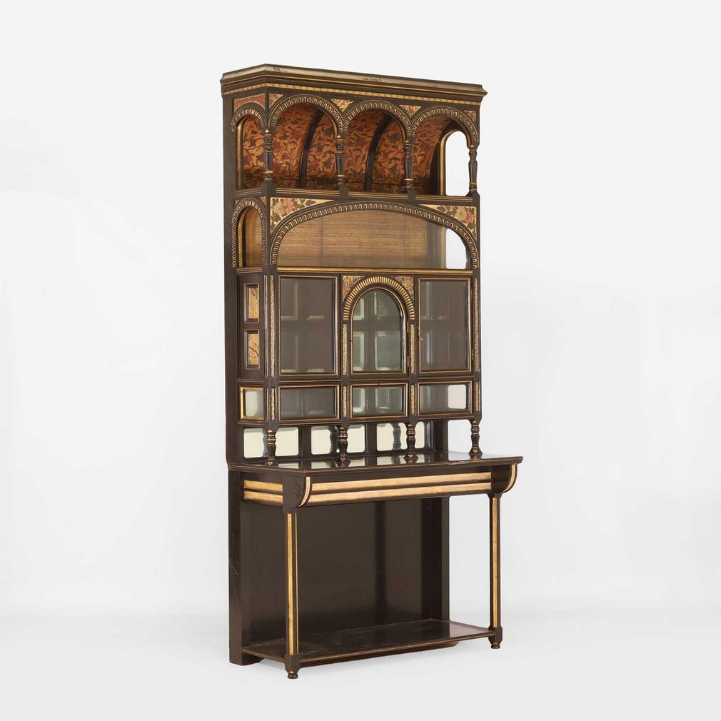Aesthetic Movement An ebonised and gilt highlighted cabinet: Aesthetic Movement An ebonised and gilt highlighted cabinet Late 19th century, with barrel vaulted top and inset with painted panels and glass cabinets, above three glass-fronted cupboards, the centra