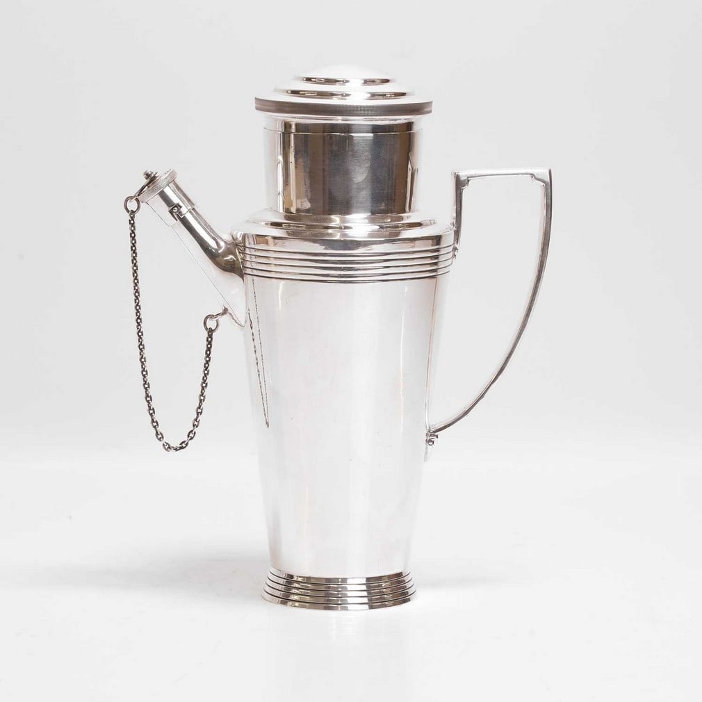 ▲ Keith Murray (New Zealander, 1892-1981) for Mappin and Webb A silver-plated cocktail shaker: ▲ Keith Murray (New Zealander, 1892-1981) for Mappin and Webb A silver-plated cocktail shaker Art Deco, c.1930, of tapering conical form, with a cover, spout, and a stopper and chain, stamped