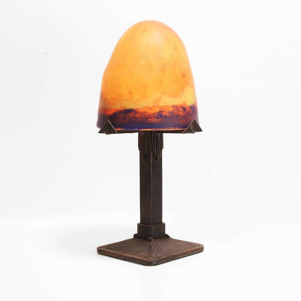 French A fer forgé table lamp: French A fer forgé table lamp The mottled orange and purple glass bullet-shaped shade, mounted on a wrought iron stand (21cm wide, 43.5cm high) Condition Report: Working, some rust is