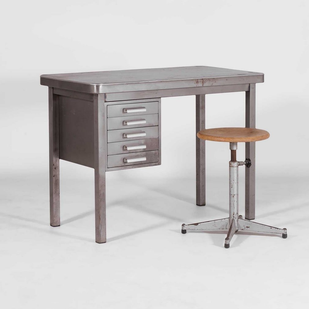 A steel desk and a stool c.1950s: A steel desk and a stool c.1950s Fitted with five drawers, on square stile legs with rubber feet, the adjustable stool with a laminated oak seat on a base with four legs (The desk: 95cm wide, 50cm