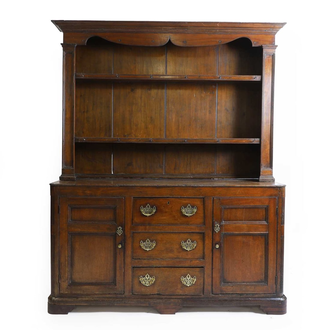 An oak dresser,: An oak dresser, early 19th century, the panelled back with a shaped frieze over two shelves with original hooks, within square pilasters, the base with three central drawers flanked by six drawers wi