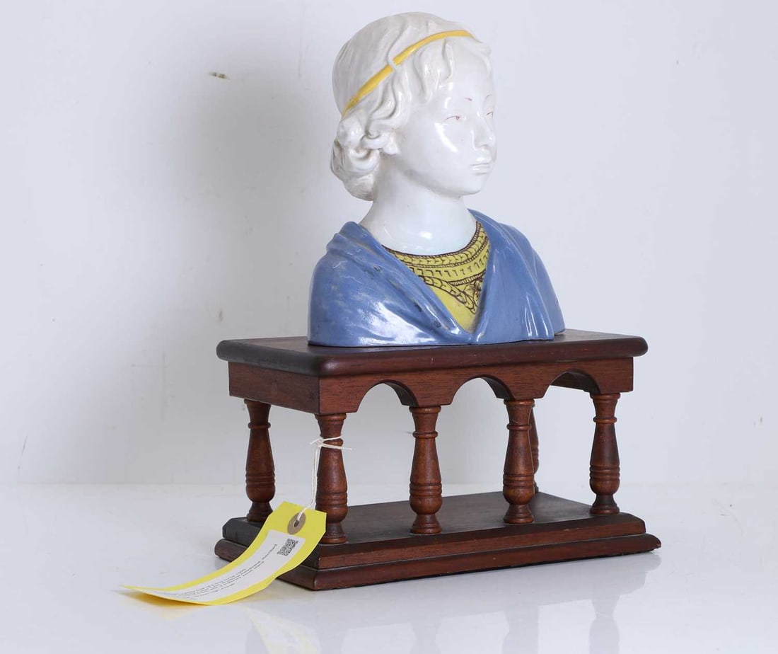 A Cantagali pottery bust of a boy Circa 1900: A Cantagali pottery bust of a boy Circa 1900 Modelled wearing a blue tunic, a yeloow headband, inscribed with the cockerel mark, with a matched wood stand 19.5cm high, 32.5cm high overall2Condition R