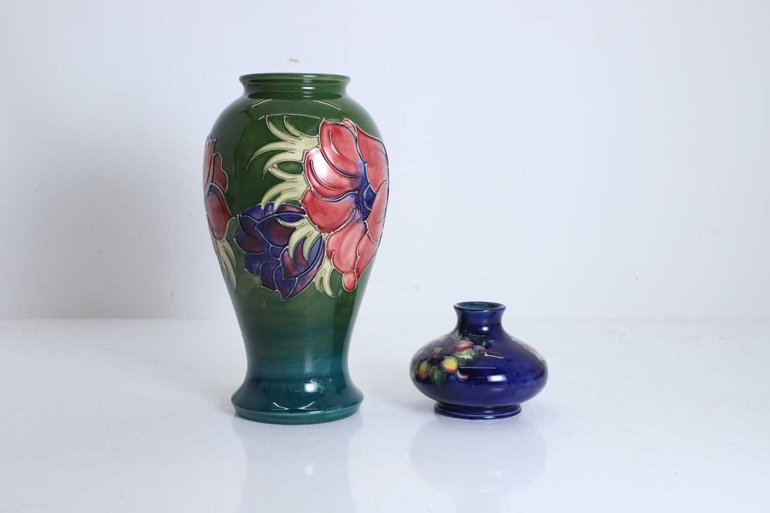 A Moorcroft Anemone pottery vase, 20th century: A Moorcroft Anemone pottery vase, 20th century On a green ground, With stamped and incised marks to the base, together with a blue ground Moorcroft squat vase, With stamped and incised marks to the
