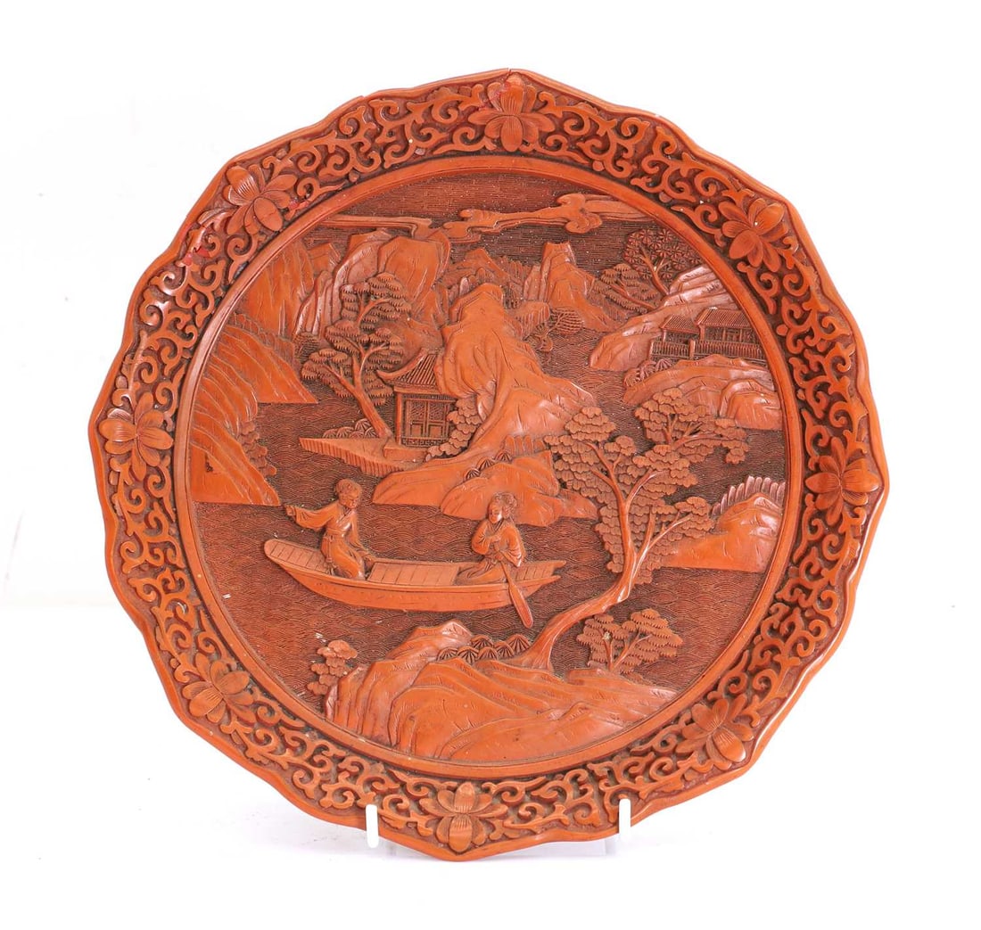 A Chinese cinnabar dish, 20th century,: A Chinese cinnabar dish, 20th century, Decorated to the main field with a lakeside scene, and with a shaped floral border, the lacquered base with carved four charcter mark 24.2cm diameterCondition R