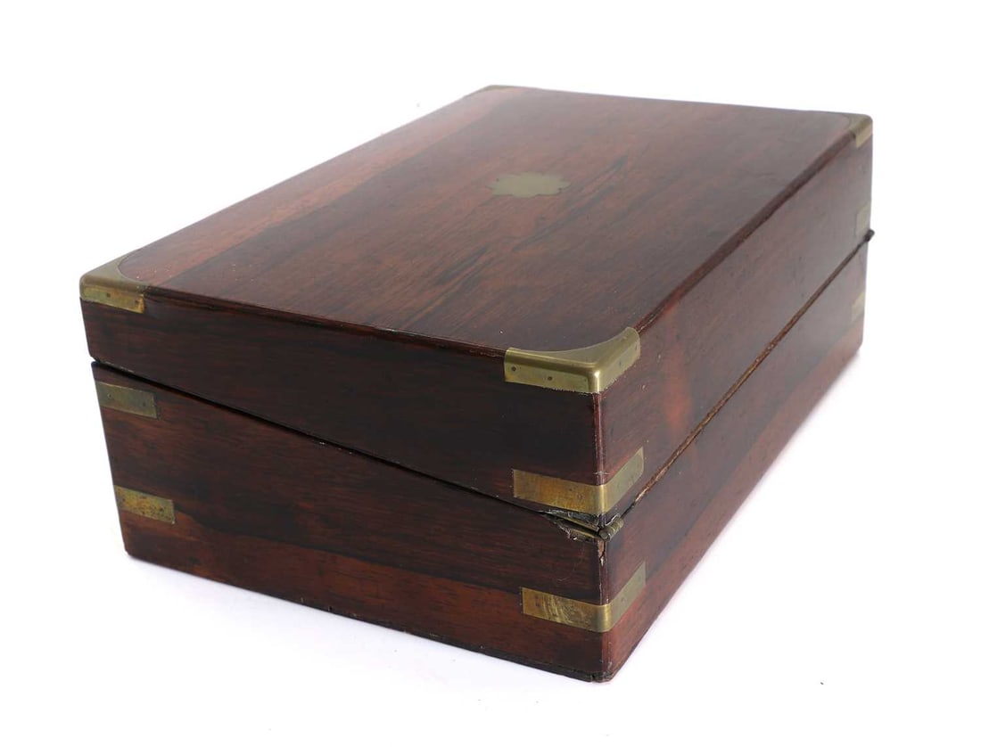A Victorian rosewood writing slope, Late 19th century: A Victorian rosewood writing slope, Late 19th century with brass bounding, and shaped black cartouche to the lid, with green baise interior slope 36cm wide, 23.5cm deep, 13.2cm highCondition Report: