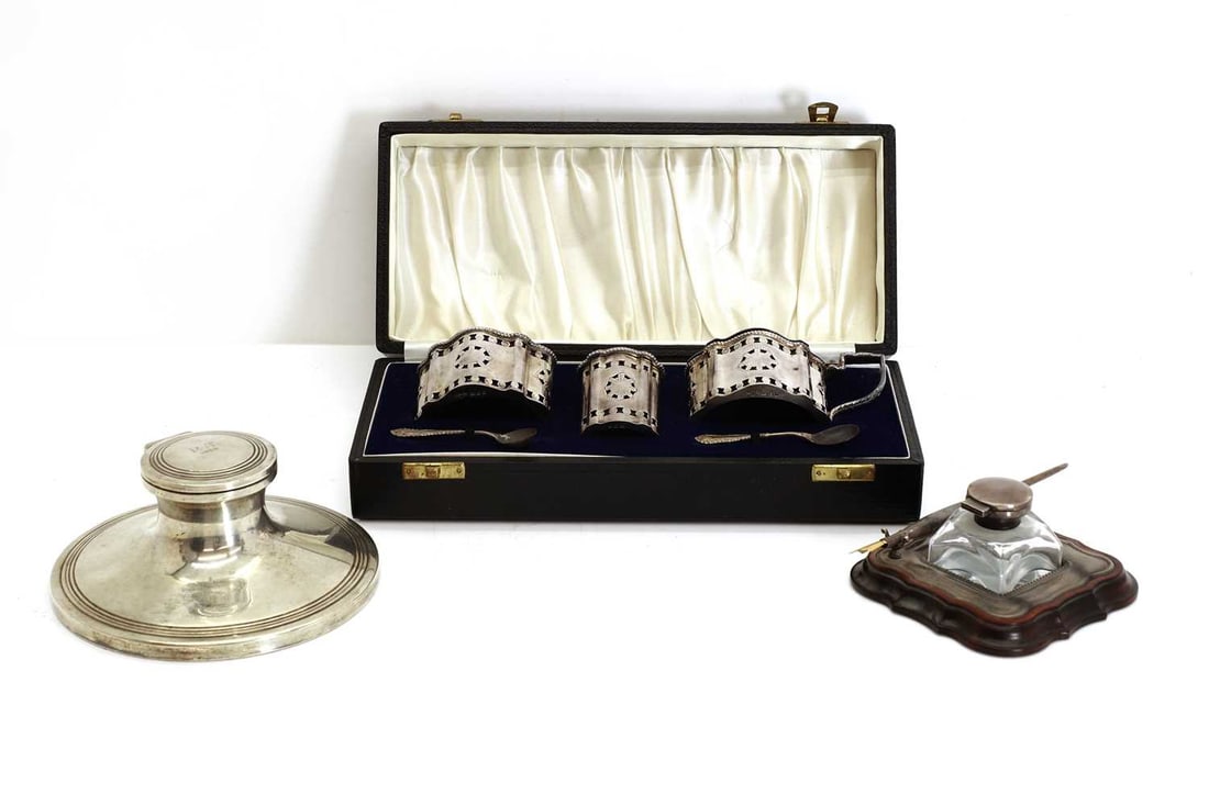 A three-piece silver condiment set,: A three-piece silver condiment set, London, 1972, with a pair of matched spoons, cased, a silver capstan inkwell, and a silver-mounted pen stand, with an inkwell salts, 7.5cm wide, inkwell, 15cm diam