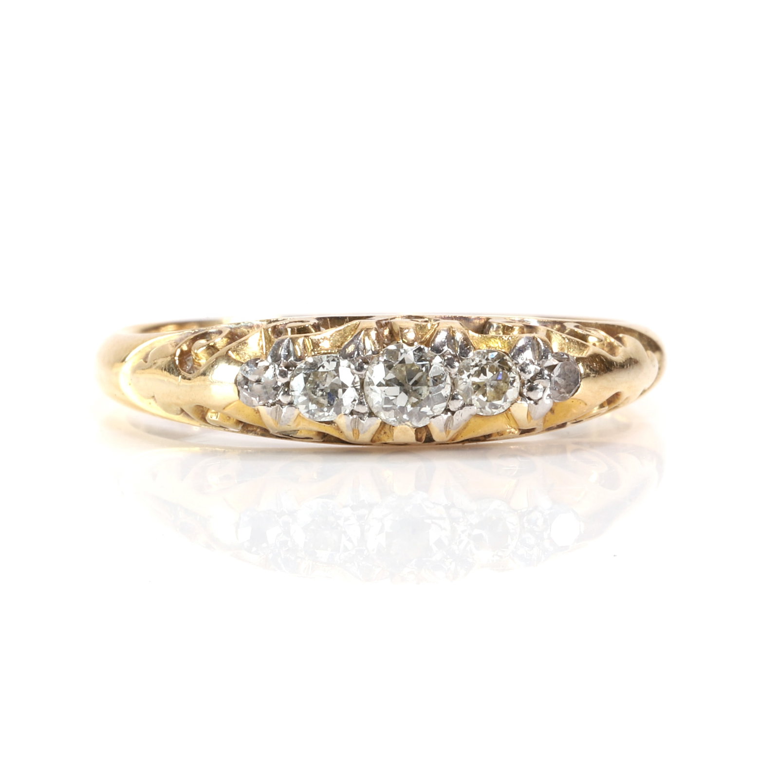 An Edwardian diamond five stone ring,: An Edwardian diamond five stone ring, with a graduated line of old cut diamonds, to a carved scrollwork mount and shoulders, with a 'D' profile shank, stamped 18ct, tested as approximately 18ct gold (