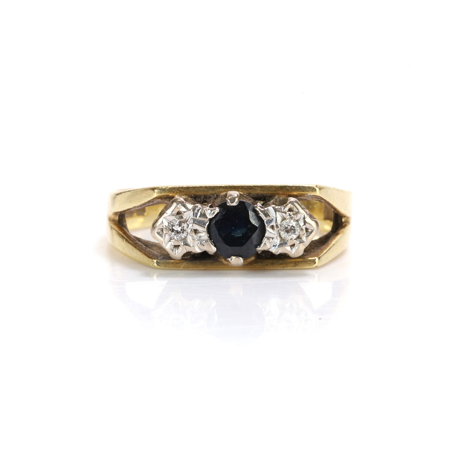 An 18ct gold sapphire and diamond ring,: An 18ct gold sapphire and diamond ring, of split shoulder design, set to the centre with a round cut sapphire and two round brilliant cut diamonds, mounted in 18ct gold, hallmarked London 1978 (Ring