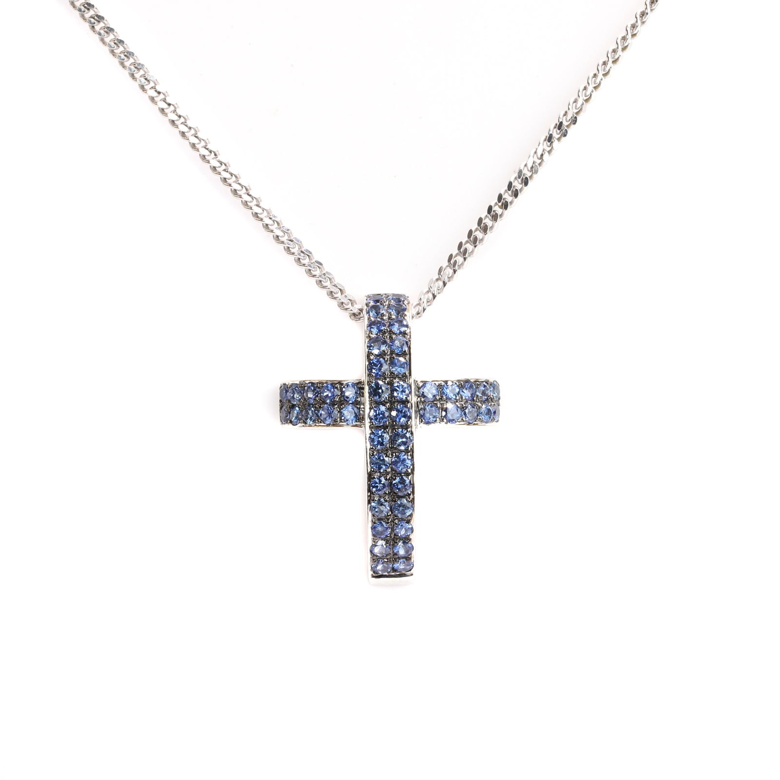 An 18ct white gold sapphire pendant necklace,: An 18ct white gold sapphire pendant necklace, the openwork pendant in the form of a stylised cross, bead set throughout with circular cut sapphires, suspended by a file curb link chain marked Unoaerre