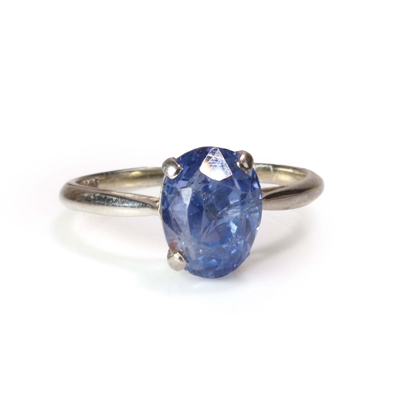 A sapphire single stone ring,: A sapphire single stone ring, the native cut sapphire claw set between chenier shoulders to a plain hoop, in white metal stamped 18ct, testing as approximately 18ct gold (Ring size N½; 3.3g)