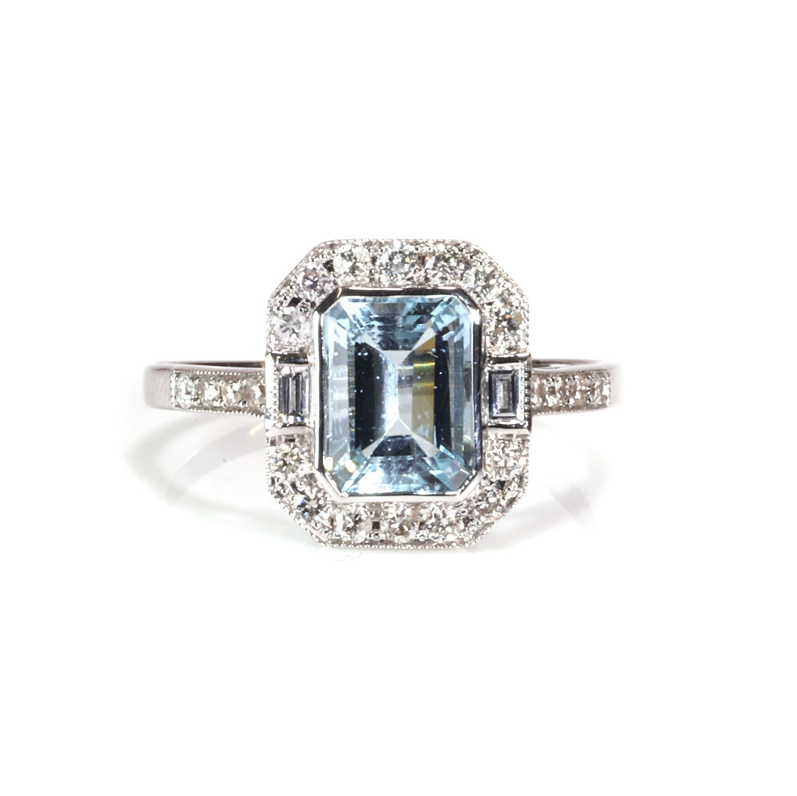 An 18ct white gold aquamarine and diamond cluster ring,: An 18ct white gold aquamarine and diamond cluster ring, bezel set to the centre with a rectangular step cut aquamarine, accented to each side by a baguette cut diamond and with a surround of round bri