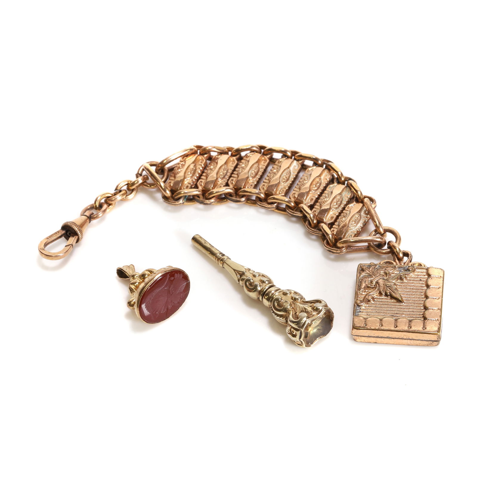 A small group of antique rolled gold implements,: A small group of antique rolled gold implements, comprising a rolled gold carnelian intaglio fob seal, a rolled gold watch key, and a rolled gold watch chain (3) Condition Report: 26.82g total. Wear t