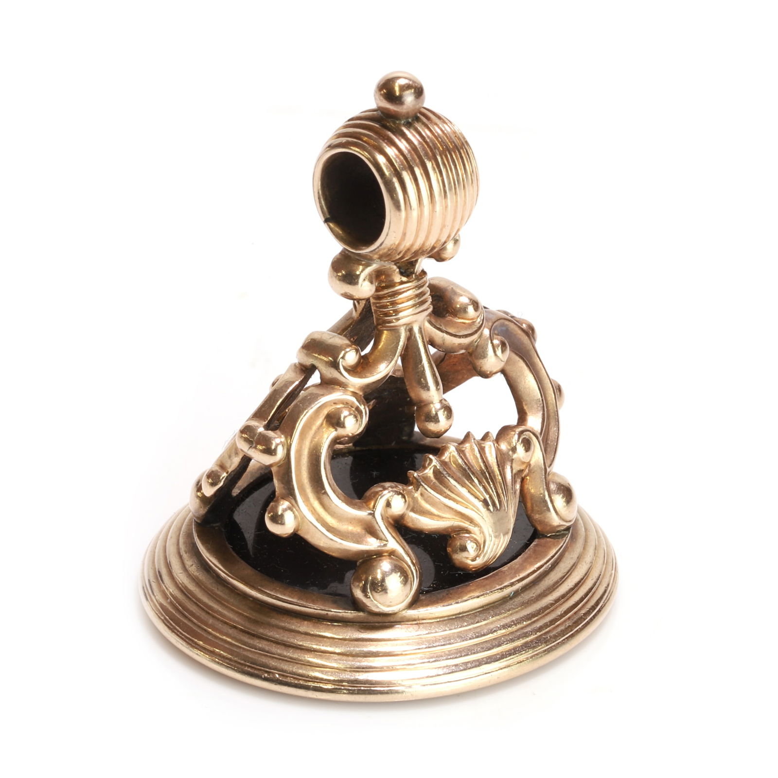 A intaglio fob seal,: A intaglio fob seal, the oval carved intaglio, bezel set to a pierced seashell and scrollwork mount, with a fixed reeded bale, tested as approximately 14ct gold (Length 3.3cm; 17.2g) Condition Report: