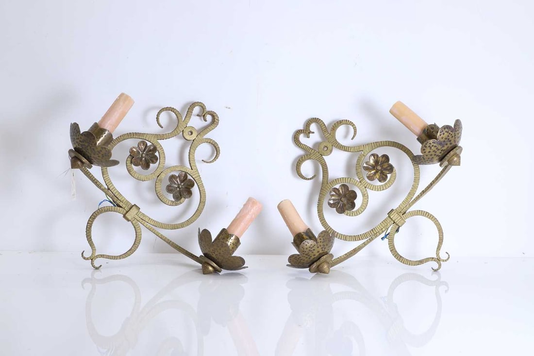 A pair of gilt iron wall lights, Mid-century,: A pair of gilt iron wall lights, Mid-century, with two branches with shaped reserves and floral appliques, converted for electricity with faux wax candles 41cm wide, 38cm high 2