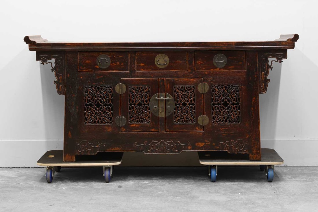 A Chinese hardwood sideboard, 20th century,: A Chinese hardwood sideboard, 20th century, the plain top, with upturned ends and pierced brackets, fitted with three drawers, over a pair of pierced doors, and flanked with further pierced panels 18
