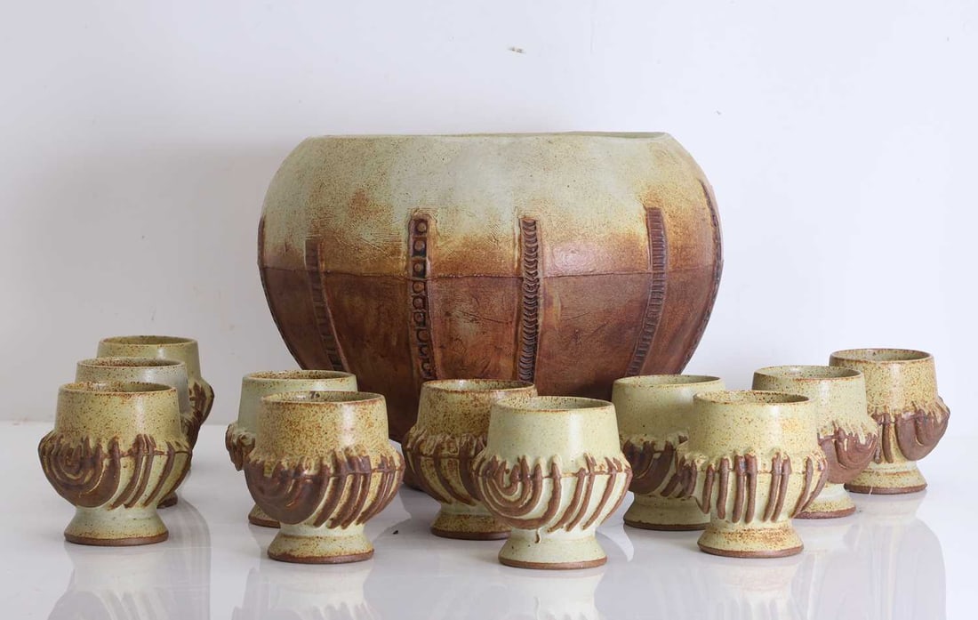 A Bernard Rooke stoneware punch bowl and goblets, Circa 1973: A Bernard Rooke stoneware punch bowl and goblets, Circa 1973 The bowl with eleven goblets, decorated in a two-tone colour palette and with low relief banding Bowl, 32cm diameter, 25cm high;