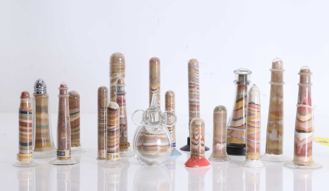 A collection of Isle of Wight coloured sand glass vessels, 20th century / 21st century,: A collection of Isle of Wight coloured sand glass vessels, 20th century / 21st century, all with shaped glass cases, including ribbed examples, and also one in a salt shaker, and one shaped as an