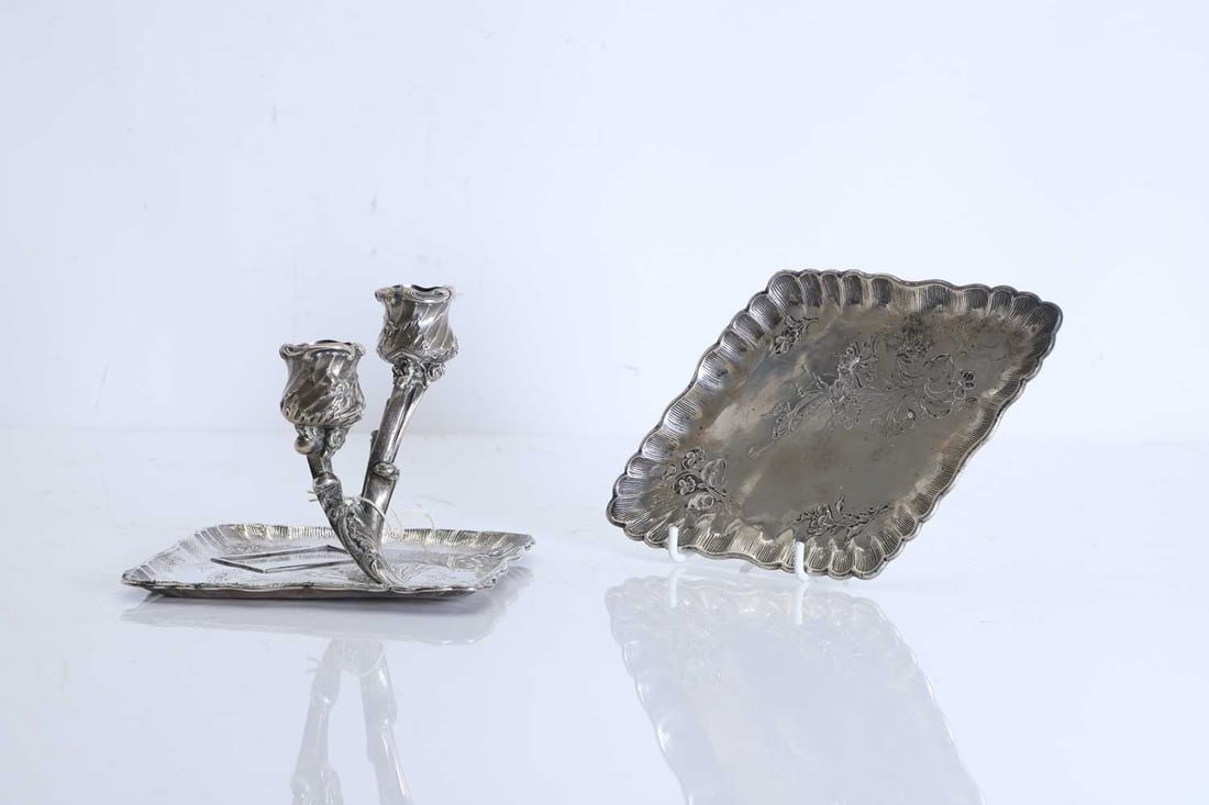 An Austrian silver chamberstick, 20th century: An Austrian silver chamberstick, 20th century the shaped rectangular drip tray with scalloped rim and fluted border, chased with foliate scrolls and flowering sprays, centred with a raised