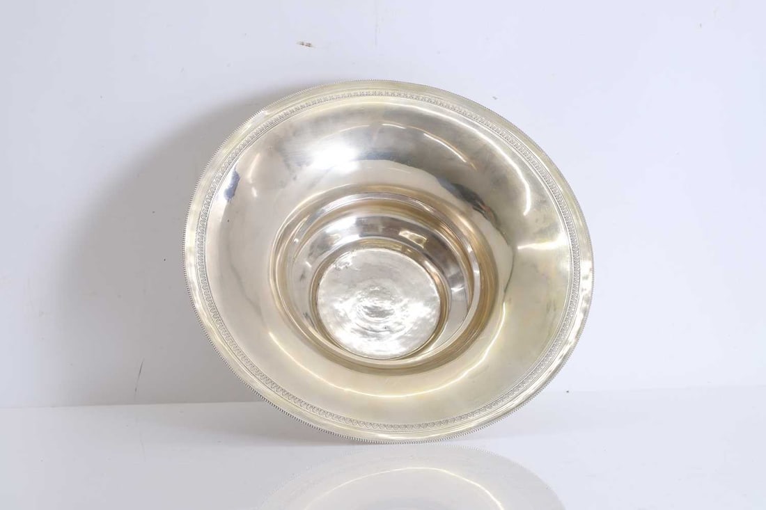 An Egyptian silver bowl, 20th century,: An Egyptian silver bowl, 20th century, marked Beni Souef 1938, the broad bowl with stepped central well, the rim with fine beaded edge, and a band of repeating palmettes 31cm diameter; 
