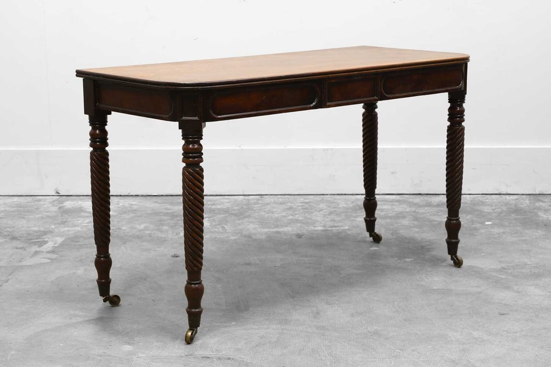 A Regency mahogany console table, Early 19th century,: A Regency mahogany console table, Early 19th century, the reeded top above sunken tabletted frieze on turned spiral twist supports descending onto castors, adapted 121cm wide, 54cm deep, 72cm high
