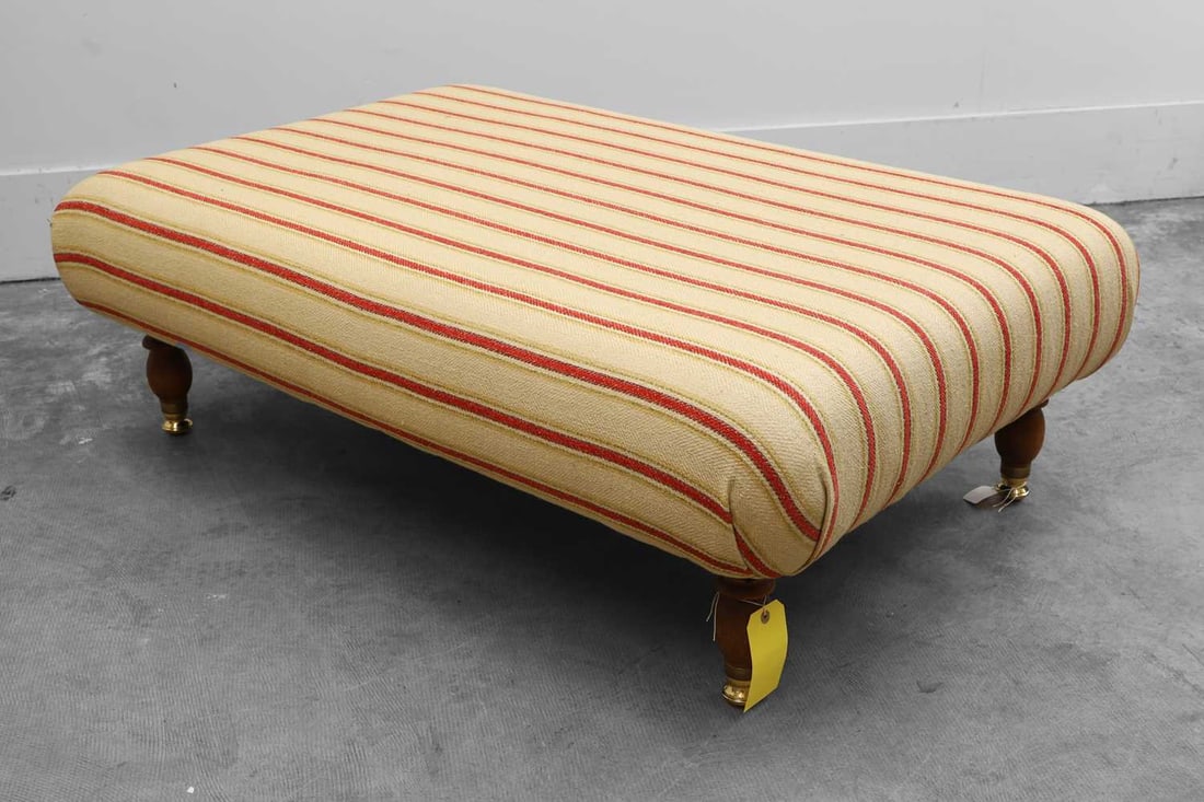 An oversized footstool, 20th century,: An oversized footstool, 20th century, on turned legs terminating in brass castors, upholstered in striped fabric 130cm wide, 84cm deep, 44cm high