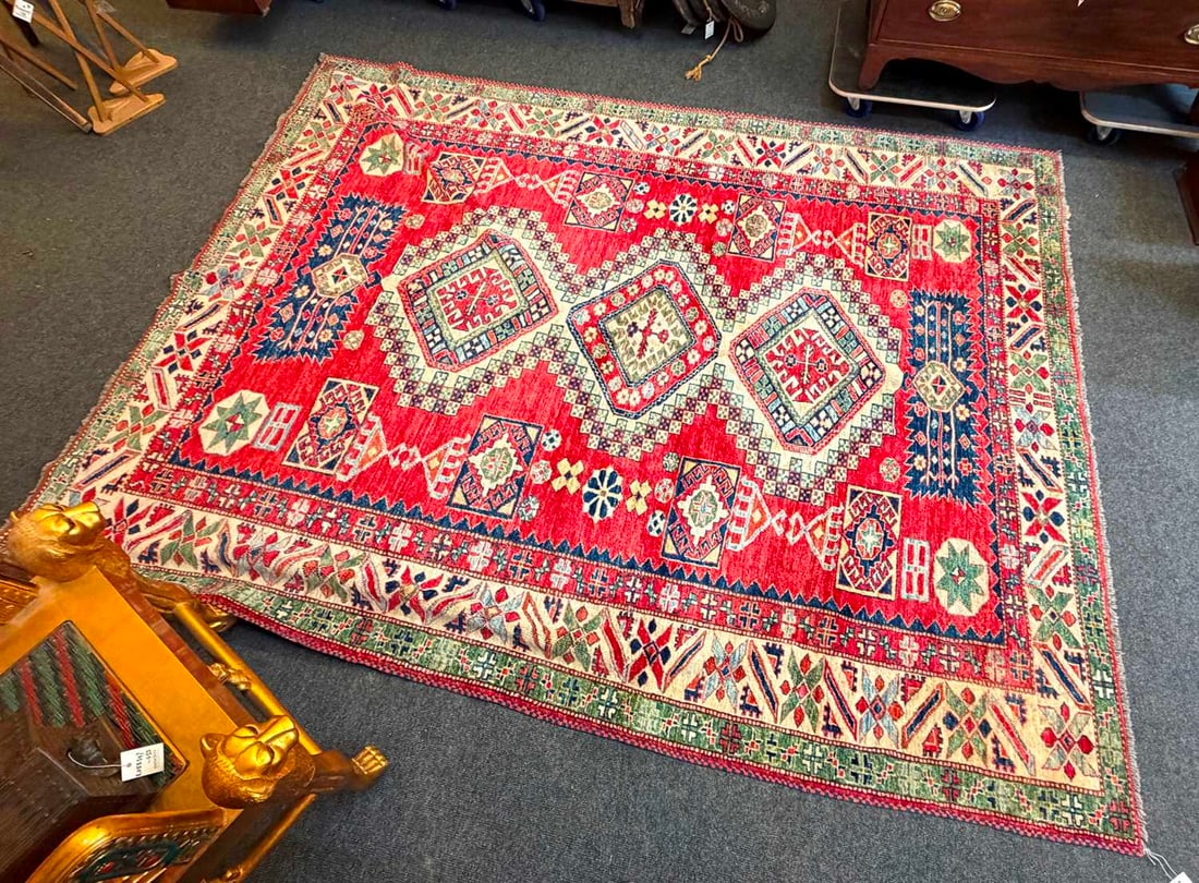 A wool carpet of Kazak design, Of recent manufacture,: A wool carpet of Kazak design, Of recent manufacture, woven with repeating geometric motifs to a red field 290 x 230cmCondition Report: General light wear to the pile. Colours appear in good order. S
