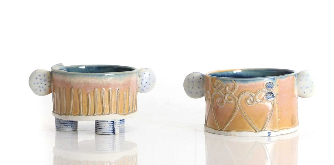 A near pair of Sarah Dunston ceramic pots, 21st century,: A near pair of Sarah Dunston ceramic pots, 21st century, both with beige ground with tubeline decoration, and circular twin handles, the smaller example raised on three feet The larger, 13cm wide;