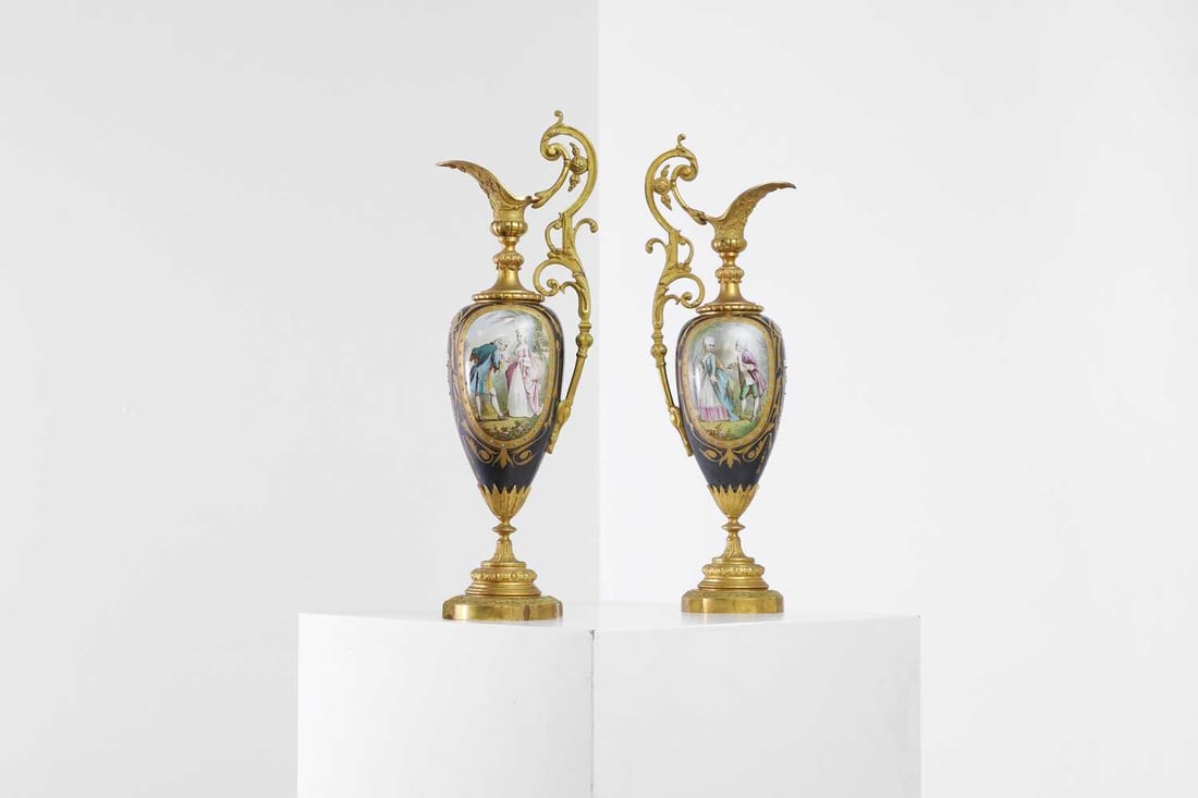 A pair of ormolu-mounted porcelain ewers, 19th century,: A pair of ormolu-mounted porcelain ewers, 19th century, French, each of ovoid form, with oval reserves decorated with 18th-century figures and pastoral scenes, within scrolling gilt foliage on a